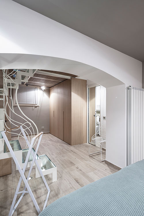 Bedroom with gorgeous glass staircase leading to the upper level in a beautiful Italian apartment by Archiplan Studio