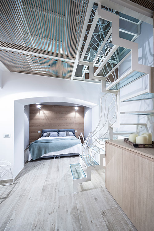 Stylish bedroom design and gorgeous glass staircase in a beautiful three-level Italian apartment by Archiplan Studio