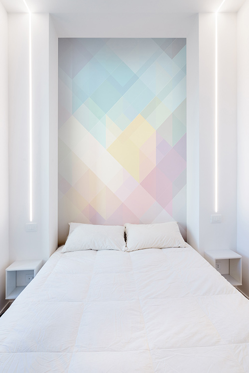 Beautiful white bedroom design with colorful wall in a minimalist apartment in Rome, Italy