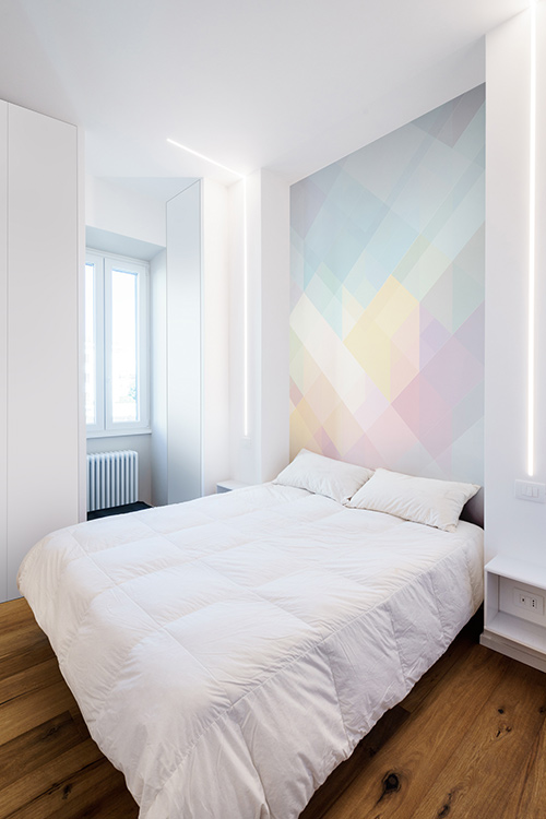 Beautiful white bedroom design idea with a colorful wall in a minimalist apartment in Rome, Italy by Brain Factory - Architecture & Design