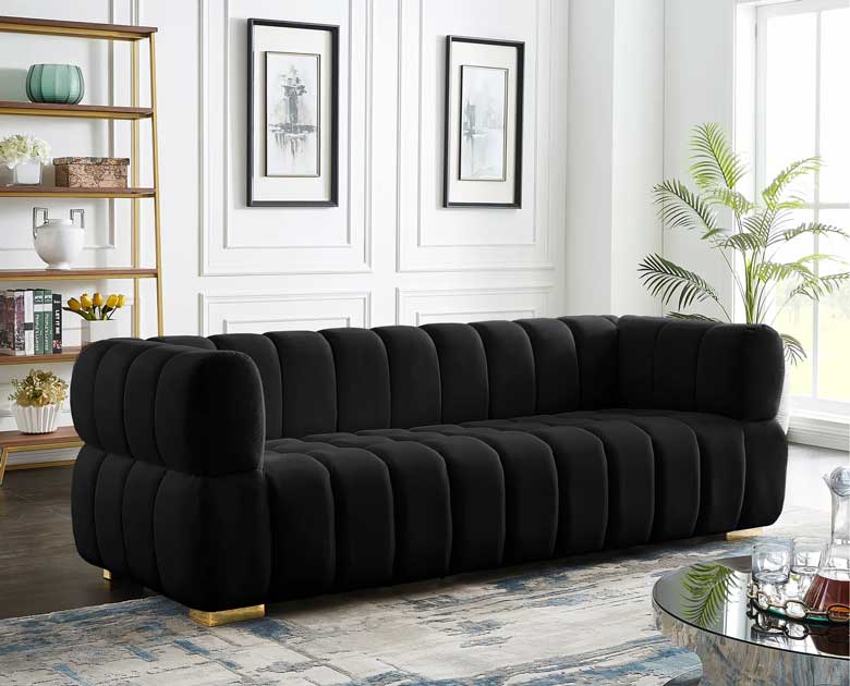 Black velvet sofa with deep biscuit tufting and gold legs