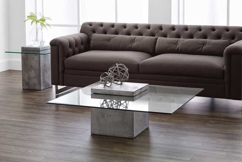 Industrial-modern coffee table, defined by a bold concrete block base and finished with a contrasting tempered-glass top