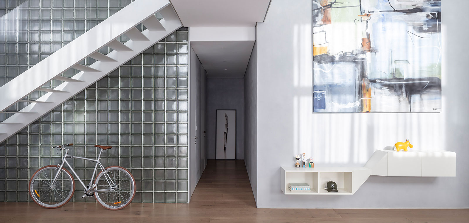 A glass block wall transfers light and creates reflections in this Tel Aviv duplex apartment