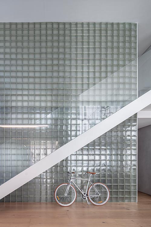 A glass block wall transfers light and creates reflections in a duplex apartment