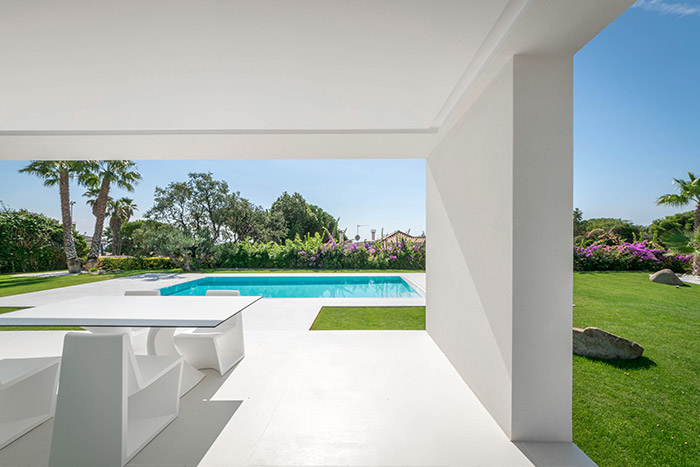 View of swimming pool and outdoor garden from dining area inside modern house outside Barcelona, Spain