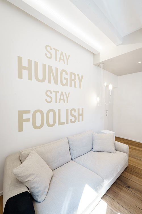 Beautiful living room design with inspirational wall writing in a minimalist apartment with all-white interior in Rome, Italy