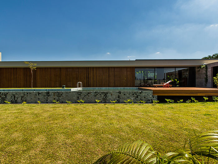 This wooden and concrete single-family house with stunning pool by mf+arquitetos, located near Sao Paulo, was inspired by Brazilian modernism