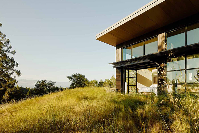 Modern home in California's wine country for a luxurious indoor-outdoor lifestyle - bedroom opens up to exterior through massive glass walls