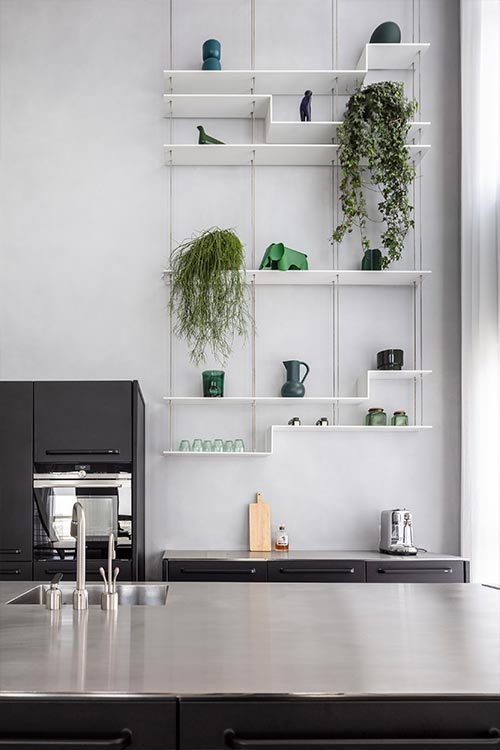 Black kitchen design with modern shelving in a bright duplex apartment