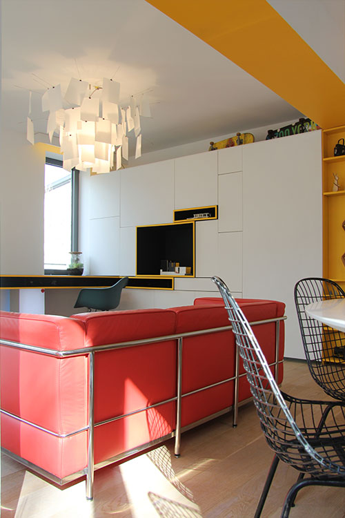 Red sofa and modern furniture add color to this apartment located in Belgium