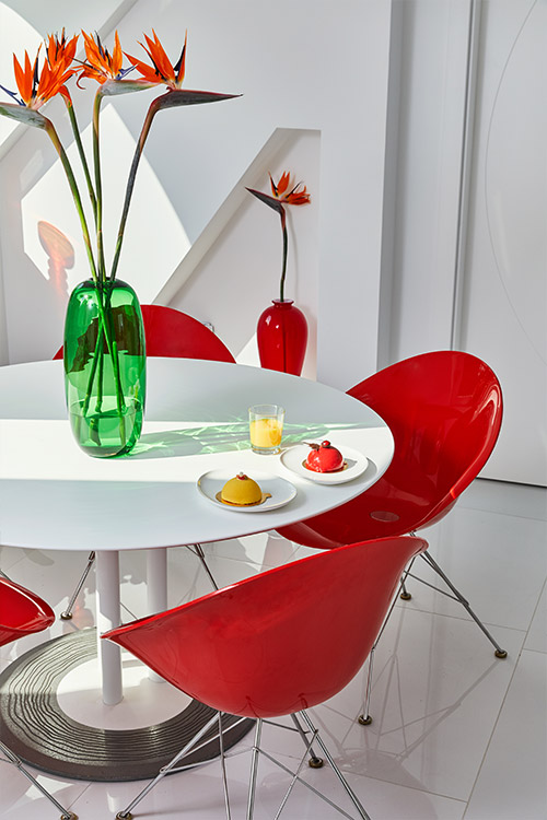 Glossy red dining chairs add color in renovated apartment