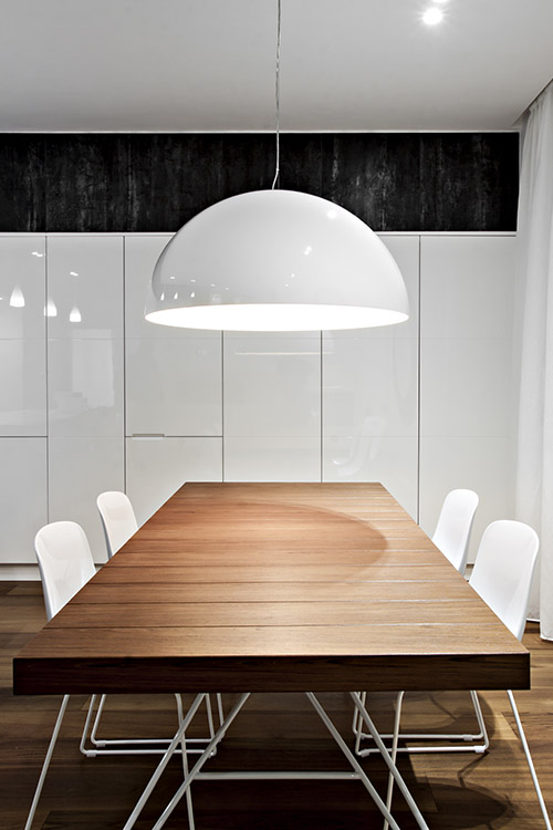 This modern dining room has a black and white palette and custom cabinets - the renovated apartment is located in Italy and was designed by  Michelangelo Olivieri / m12AD