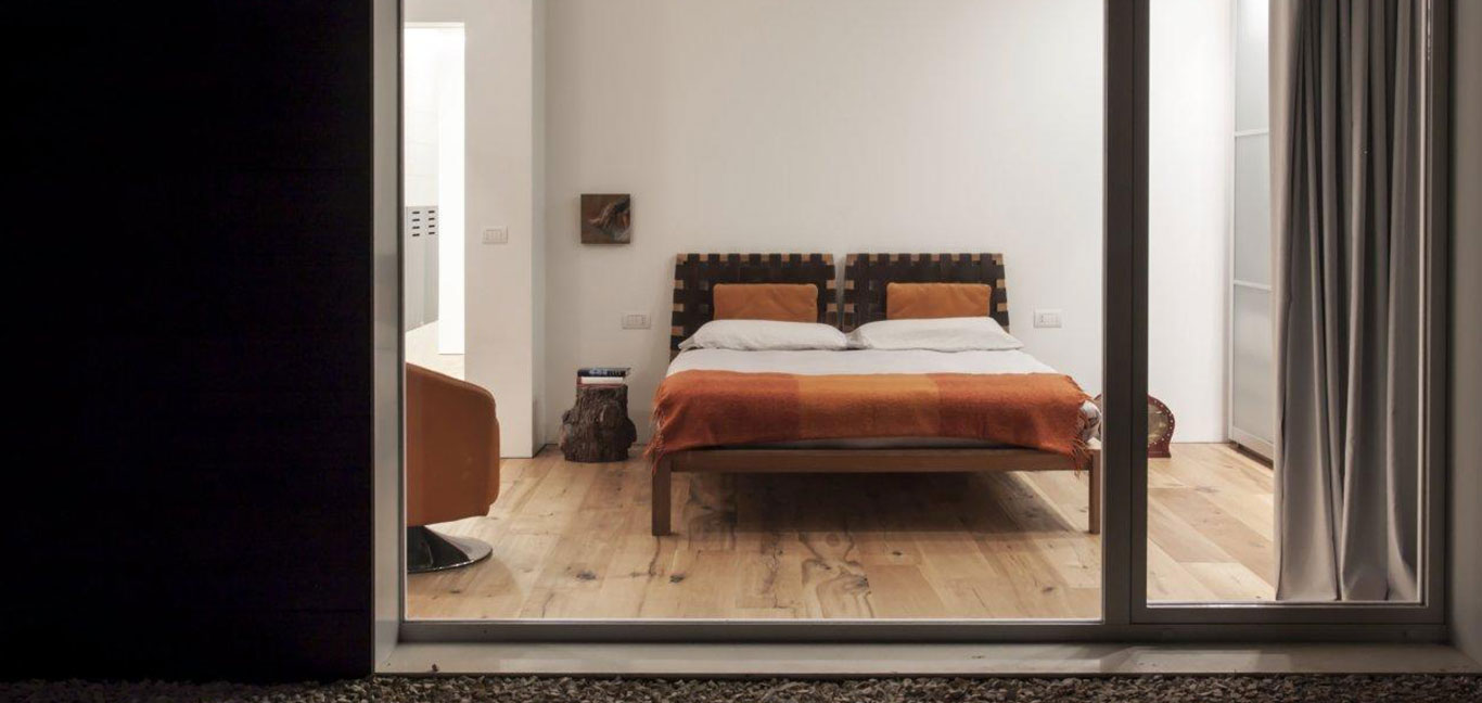 Minimalist bedroom in a sophisticated home in perfect balance with the surrounding environment - located in Italy, renovated by m12 AD