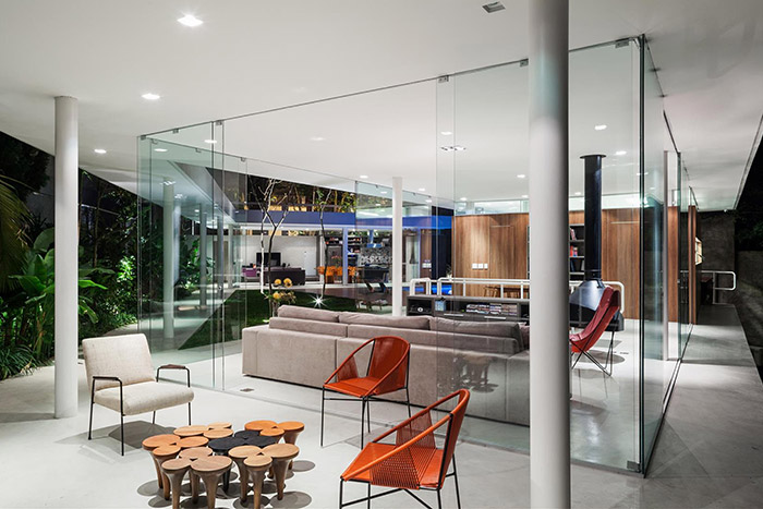 Incredible living room design with lots of glass that opens up to the kitchen, patio with pool and lush garden - designed by FGMF Architects