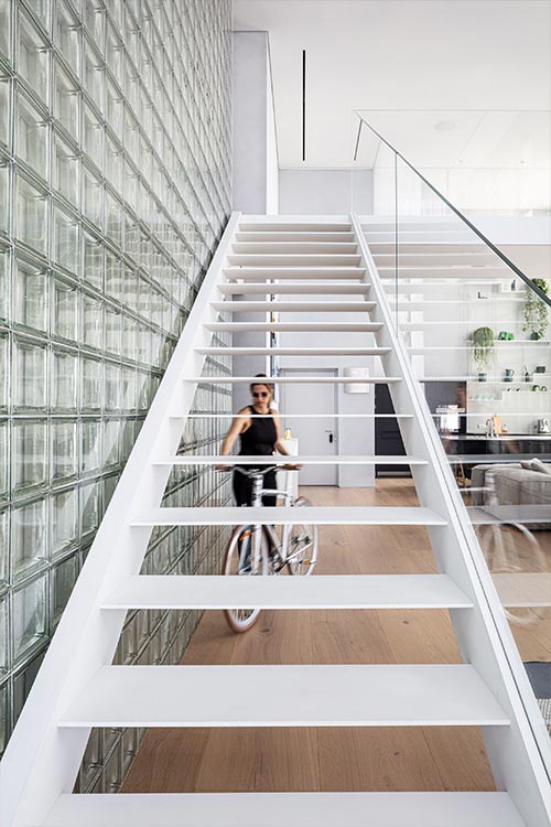 Bright duplex apartment with glass block wall and white staircase